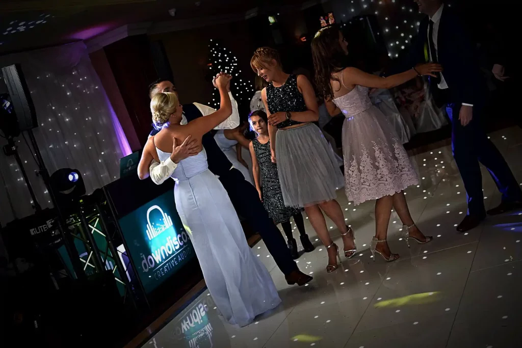 A crowded white LED dance floor hire at a wedding reception in Northern Ireland with guests dancing